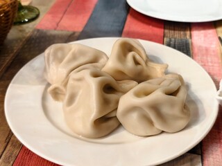 Plate of khinkali dumplings ready to eat on a colorful wooden table in a restaurant setting indoors