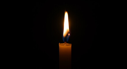 Candle flame glowing in darkness symbolizing hope and tranquility  