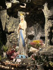 The Blessed Virgin Mary. Saint sculpture isolated on candles background. Virgin Mary statue in a Catholic church. Mother Mary pray. Blessed virgin statue. 