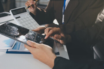 Focused young businessman signing agreement with skilled lawyer in eyeglasses. Concentrated financial advisor showing place for signature on paper contract document to male client at meeting in office