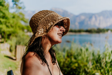 young mid adult tourist woman enjoys holidays at a mountain lake in Levico on a sunny summer day smiling