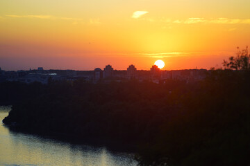 Sunset from Kalemegdan: view of the Danube, sun setting on the horizon, multi-story buildings and...