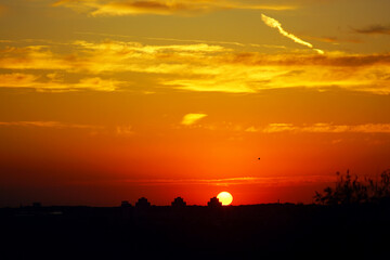 Dramatic sunset with glowing orange and red sky. Sun setting beyond dark horizon. Evening landscape with silhouettes from Belgrade. Concept of nature beauty, calm atmosphere and urban inspiration