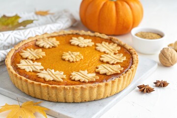 Warm Pumpkin Pie With Decorative Crust and Autumn Decorations on a Table
