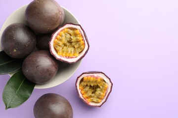 Fresh passion fruits with green leaves on violet background, flat lay. Space for text