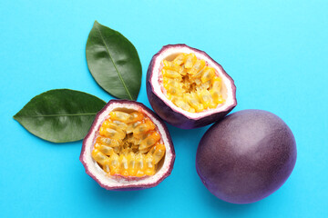 Fresh passion fruits with green leaves on light blue background, above view