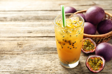 Tasty passion fruit drink and fresh fruits on wooden table, closeup. Space for text