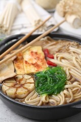 Tasty ramen with enoki and king oyster (eryngii) mushrooms on light grey table, closeup