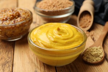 Different types of mustard on wooden table, closeup