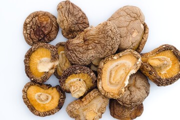 An artistic display of dried shiitake mushrooms on white, emphasizing their textured surfaces and organic colors.