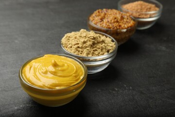 Different types of mustard on black table, closeup