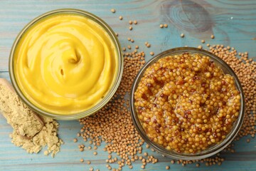 Different types of mustard on light blue wooden table, flat lay