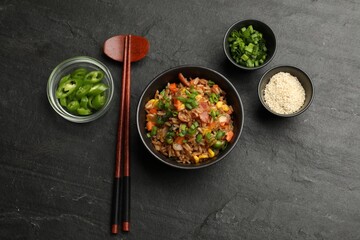 Delicious fried rice in bowl served on grey textured table, flat lay