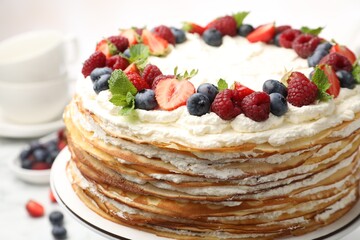 Delicious crepe cake with fresh berries on white table, closeup