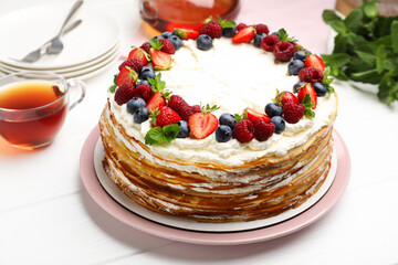 Delicious crepe cake with fresh berries served on white wooden table