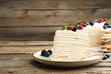Piece of tasty crepe cake with berries served on wooden table, closeup. Space for text