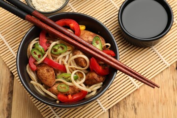 Tasty noodles with chicken and vegetables served on wooden table, flat lay