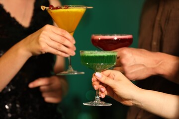 Friends clinking glasses with cocktails in bar, closeup