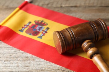 Judge's gavel and flag of Spain on wooden table, closeup