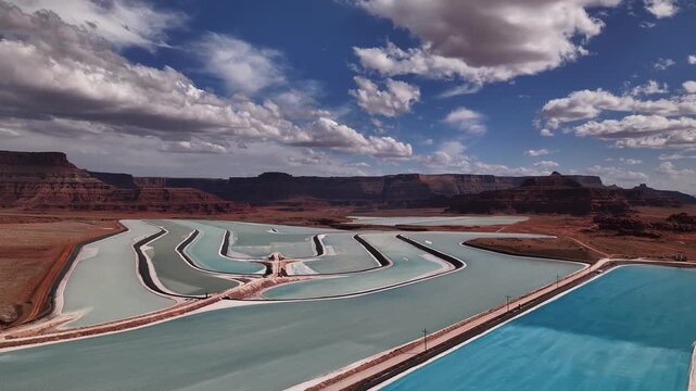 Aerial view of the vibrant turquoise potash ponds contrasting with the arid red rock landscape, creating a stunning visual mosaic, Moab, Utah, United States.