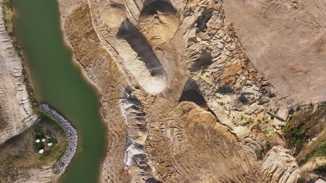 Aerial view of a quarry showcasing textures and contrasting earthy tones alongside a green pond, Br&uuml;ssow Uckermark, Brandenburg, Germany.