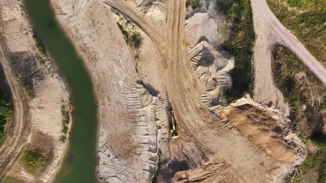 Aerial view of the stark, contrasting textures of a winding river snaking through a sandy excavation landscape, Penkun, Brandenburg, Germany.