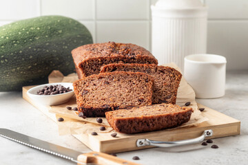 Chocolate zucchini bread cake sliced. Moist chocolate cake with grated zucchini, cocoa powder and chocolate chips on white tile kitchen background
