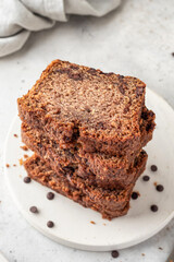 Chocolate zucchini bread cake sliced. Moist chocolate cake with grated zucchini, cocoa powder and chocolate chips on white kitchen background close up