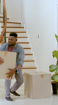 Vertical video: African American man stacking boxes at door before woman inspecting stairs