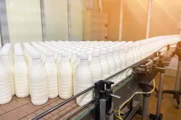 Milk packaging line with bottles on a conveyor belt in a dairy plant
