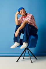 Trendy young African American man poses stylishly against a blue backdrop