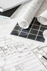 sustainable architecture tools and materials: blueprints, solar panel, wood textures, fabric swatches, and stones. Eco-friendly design, conscious construction and green innovation.