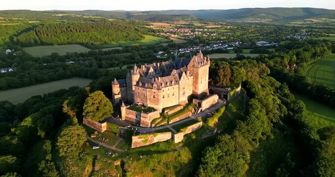 Majestic Castle Perched Atop a Verdant Hillside Bathed in Golden Hour Light.
