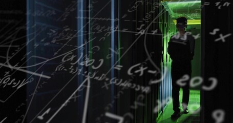 Korean engineer carrying laptop walking through server room, with racks, green LEDs, floating math