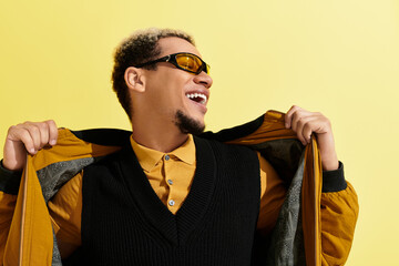 Young african american man showcases trendy style in studio against yellow backdrop