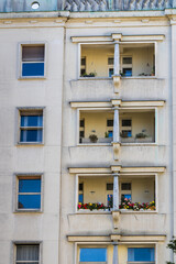 facade of a building, Four-story building facade with balconies, plants, and open windows