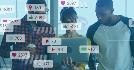 Analyzing social media icons by colleagues in casual wear in workspace, with laptop, coffee