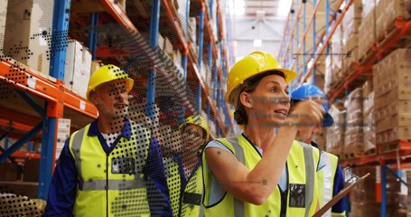 Speaking into radio, holding clipboard, warehouse worker wearing hi-vis vest in aisle, copy space