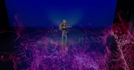 Strumming guitarist in plaid shirt playing acoustic guitar on stool on stage, with stage lights