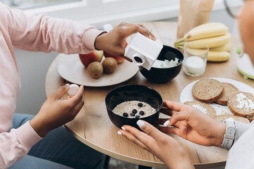 Two black women preparing oatmeal with blueberries for breakfast at home