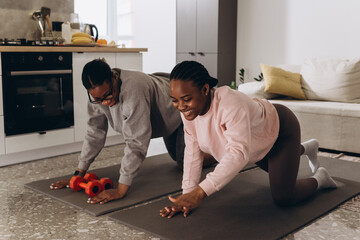 Two black women doing push-ups together at home