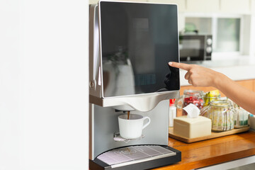 Woman hand pressing coffee machine at hotel bar counter.