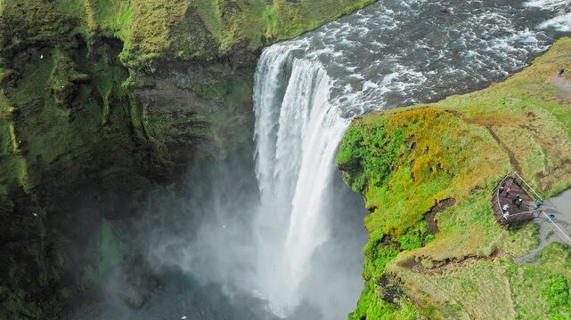 op view of Skogafoss waterfall Iceland drone aerial. 4K cinematic footage highlights turquoise water plunging into pool.