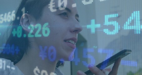 Speaking woman in casual top holding smartphone near mouth in office, with financial data overlays