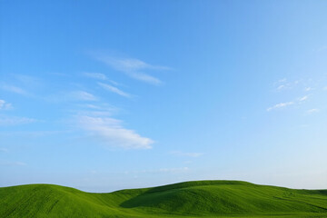 Green hills under a clear blue sky with some clouds on a sunny day