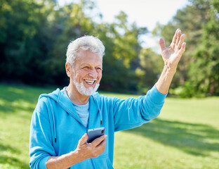 Happy active senior man having fun using smartphone and wearing sportswear, after having an exercise or running sport activity outdoors