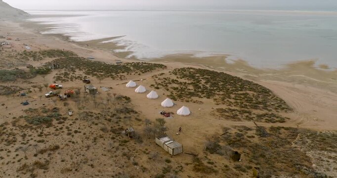 Aerial view of tents pitched near the serene Detwah lagoon, contrasting with the arid landscape, a blend of adventure and peace, Detwah, Socotra, Yemen.