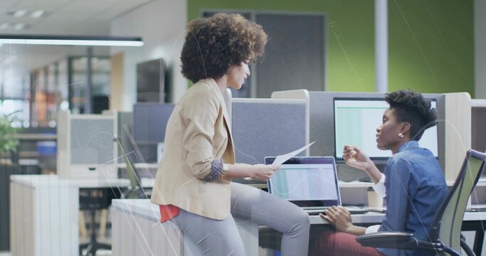 Discussing professionals in business attire collaborating at office desk, with laptop and documents