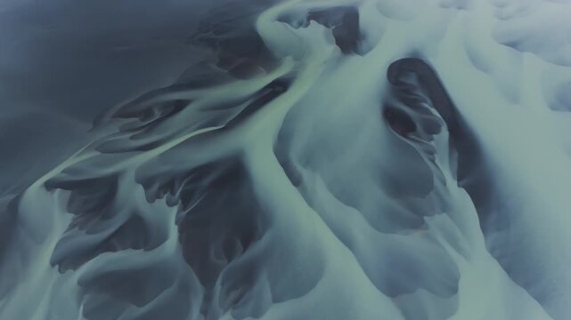Aerial view of intricate glacial river patterns carving through the landscape, creating a mesmerizing tapestry of textures and tones, Iceland.
