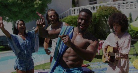 Dancing shirtless man draping striped towel by backyard pool, with guitar and picnic blanket